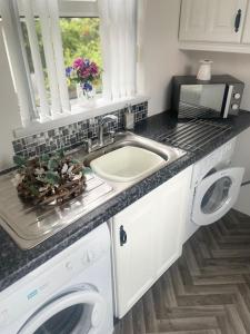 eine Küchentheke mit einer Spüle und einer Waschmaschine in der Unterkunft Mountainview Cottage in Dungiven + 24 Fotos