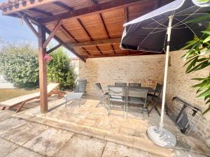 a patio with a table and chairs and an umbrella at REFUGE CHAMPETRE - Moderne & Confort - Jardin Terrasse Barbecue - Parking et Wifi Gratuit - ESPACE ET DETENTE - Parfaitement équipé - Idéal FAMILLE in Saint-Coutant-le-Grand