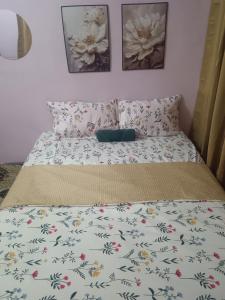 a bed with a floral bedspread and pillows on it at Madana homestay pasir puteh in Pasir Puteh +13 photos