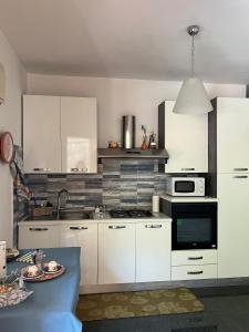 a kitchen with white cabinets and a microwave and a table at Casa vacanze Òikos Letojanni -Taormina mare in Letojanni