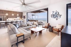 a living room with a large couch and a kitchen at Modern Boutique Condo, Ocean Views, Great Location in El Pescadero