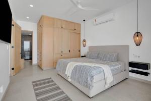 a white bedroom with a large bed and wooden cabinets at Luxury Oceanfront Condo, Resort-Style Amenities in El Pescadero +17 photos