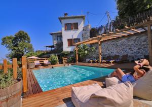 a man sitting on a couch next to a swimming pool at Adama in Mouresi