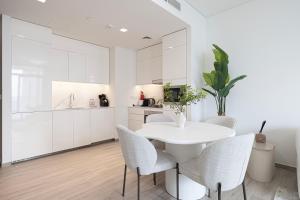 a white kitchen with a white table and chairs at Elegant 1BR with Skyline View in Creek Harbour in Dubai