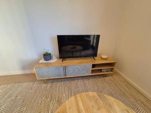 a flat screen tv sitting on top of a wooden entertainment center at Modern Comfort in Canberra's City Center - Hosted by Canstay in Canberra