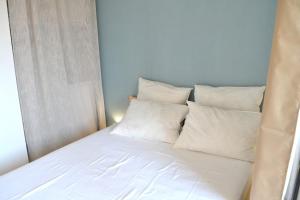 a bed with white pillows on it in a room at Le cabanon de Mirza in Sète