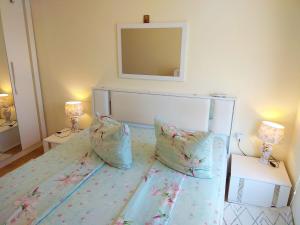 Un dormitorio con una cama con dos almohadas y un espejo. en Прекрасный апартамент с видом на море и бассейном, en Byala