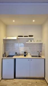a kitchen with white cabinets and a sink at Tolo Blue Bay in Tolo