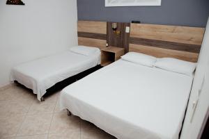 due letti in una stanza con lenzuola bianche di Hotel Real Guatapé a Guatapé