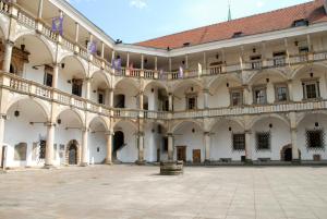 an empty courtyard of a large building with flags at Piast Castle Apartment Brzeg in Brzeg