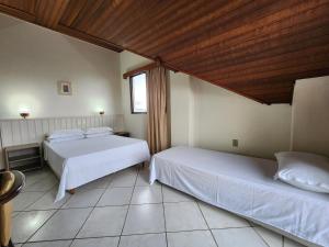 Un dormitorio con dos camas y techo de madera. en Bomar Residence, en Bombinhas