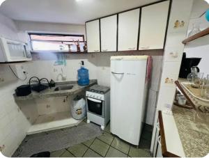 a small kitchen with a white refrigerator and a sink at Praia de Ponta Verde com lavadora, wi-fi, garagem - quarto andar in Maceió