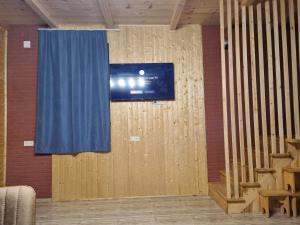 a television on a wall with a blue curtain at Gomarduli Inn გომარდული ინნ in Gomarduli