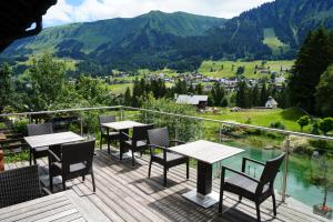 a balcony with tables and chairs and a view of mountains at Boutique Hotel Herzhof - Garni-Appartements - Adults Only in Riezlern
