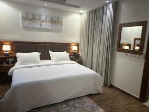 una camera da letto con un grande letto bianco e uno specchio di استديو انيق بدخـول ذاتي ad Al Kharj