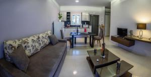 ein Wohnzimmer mit einem Sofa und einem Tisch sowie eine Küche in der Unterkunft Ionion Beach Apartment Hotel & Spa in Arkoudi