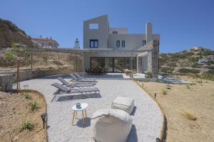 a house with chairs and a table in front of it at Theasea beachfront luxury residence in Ligaria