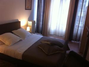 uma cama com lençóis brancos e almofadas num quarto em Hotel Residence 18 em Bruxelas