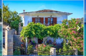 a small white house with stairs and a porch at Zeus Guesthouse in Panagia