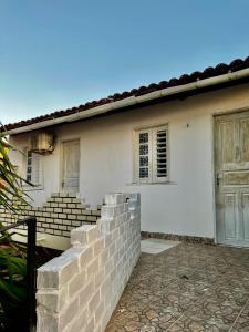 a white house with a brick wall and a door at Recanto Canoa - Canoa Quebrada in Aracati
