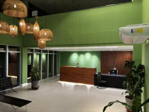 an office lobby with green walls and a reception desk at Loft Pestana Lodge - Suíte e Sala in Salvador