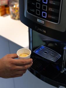 a person holding a cup of coffee in front of a microwave at SeaSide Sopot - butikowe noclegi przy plaży in Sopot