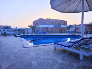 a swimming pool with a chair and an umbrella at Dolphin Continental Hotel in Quseir