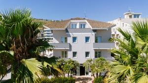 a large white building with palm trees in front of it at Hotel Caravel in Vasto