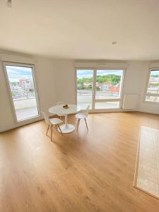 a white room with a table and chairs and windows at Élégance Parisienne in Villemomble