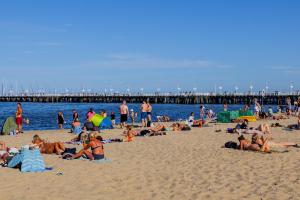 a group of people on a beach with a pier at SeaSide Sopot - butikowe noclegi przy plaży in Sopot