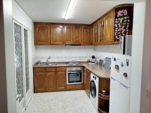 a kitchen with wooden cabinets and a white refrigerator at A Telleira in Rosal
