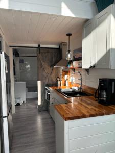 a kitchen with white cabinets and a wooden counter top at Sunrise Cabin- The Loft - secluded Beach front guest house in Sandspit