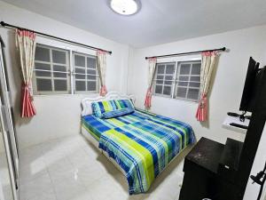 Un dormitorio con una cama y dos ventanas en K T Greenvill, en Ban Khom