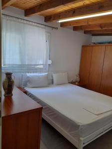 a white bed in a room with a window at Dimitra's Country House in Forest and Sea (2) in Metamorfosi