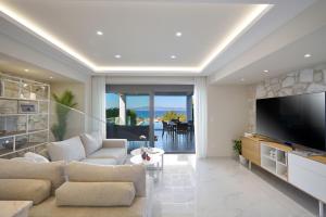 a living room with a couch and a television at Villa Paradisio 2, Pool, Sea View in Hanioti
