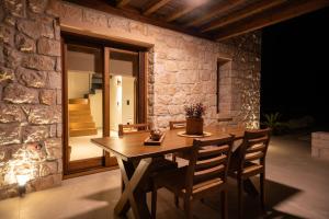 a wooden table and chairs in front of a stone wall at Candelas Suites & Nature in Ierissos