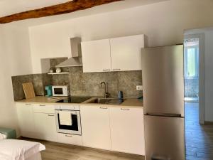 a kitchen with white cabinets and a stainless steel refrigerator at Appartamento I Canali in Rio nellʼElba