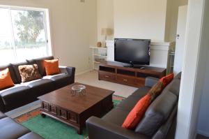 a living room with couches and a flat screen tv at BATHURST GOLDFIELDS RESIDENCE on MOUNT PANORAMA in Bathurst