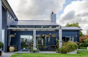 a blue house with a porch with potted plants at Ruru Lodge - Bed and Breakfast in Kinloch