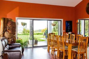 a dining room with orange walls and a wooden table and chairs at Ruru Lodge - Bed and Breakfast in Kinloch