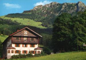 a large house on a hill with a mountain at Hotel Pfeiffermühle in Wertach