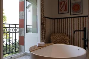 a bath tub in a room with a balcony at Villa Haute Guais, maison et table d'hôtes vue mer in Dinard