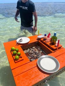 ボイペバ島にあるIlha de Boipeba kitnets para temporada - Morada dos Pássaros Boipebaの水中のテーブルの横に立っている男性