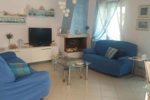 a living room with two blue couches and a tv at Any Summer garden house in Skála Nikíta