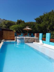 a swimming pool with blue chairs and an umbrella at A Mi Manera Apart in Merlo