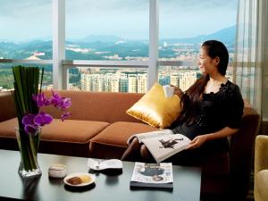 una mujer sentada en un sofá sosteniendo un libro en HJ International Hotel, en Dongguan