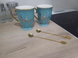 two blue and gold coffee cups and spoons on a counter at Completely new one bedroom apartment in Mirijevo