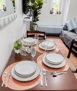 a dining room table with plates and wine glasses at 1BR By The Airport at Amani Grand Residences in Lapu Lapu City +20 photos