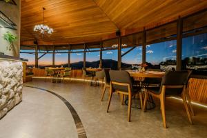 a dining room with tables and chairs and large windows at Mirante da Colyna Hotel & SPA in Monte Verde