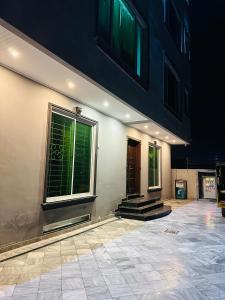 a building with three windows and some stairs at The Luxury Girls Hostel- LDA Avenue in Lahore